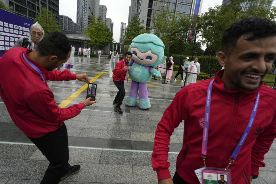Athletes from Yemen take photograph with a mascot of the 19th Asian Games during the team welcoming ceremony at the 19th Asian Games in Hangzhou, China, Thursday, Sept. 21, 2023. The Asian Games are an attention grabber. For starters, they involve more participants than the Summer Olympics. Organizers say more than 12,000 will be entered as the opening ceremony takes place Saturday, Sept. 23 in the eastern Chinese city of Hangzhou. (AP Photo/Ng Han Guan)