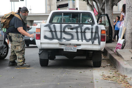 Raul Gonzalez paints cars with washable spray paint before members of the Teamsters Union participate in a tractor trailer caravan surrounding the LA Metro Detention Center in support of port truck drivers and others threatened by deportation if the courts or congress don't stop the termination of Temporary Protected Status (TPS) in Los Angeles, California, U.S. October 3, 2018. REUTERS/Kyle Grillot