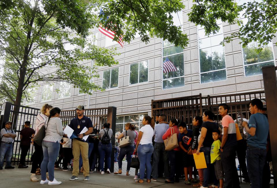 In this June 12, 2019, photo, an Immigration and Customs Enforcement official assists people waiting to enter the building that houses ICE and the immigration court in Atlanta. U.S. authorities are fast-tracking families' cases through immigration courts in a bid to discourage many from making the journey to seek refuge in the United States. (AP Photo/Andrea Smith)