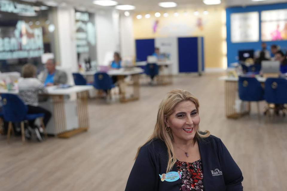 Odalys Arevalo, one of the managing partners of Las Madrinas de los Seguros (Spanish for "The Godmothers of Insurance,"), a health insurance agency serving Spanish-speaking clients, speaks during an interview as insurance agents work behind her inside their main location at a shopping center in Miami, Tuesday, Dec. 5, 2023. (AP Photo/Rebecca Blackwell)