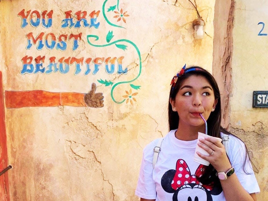 saira drinking a drink in animal kingdom in front of you are most beautiful sign