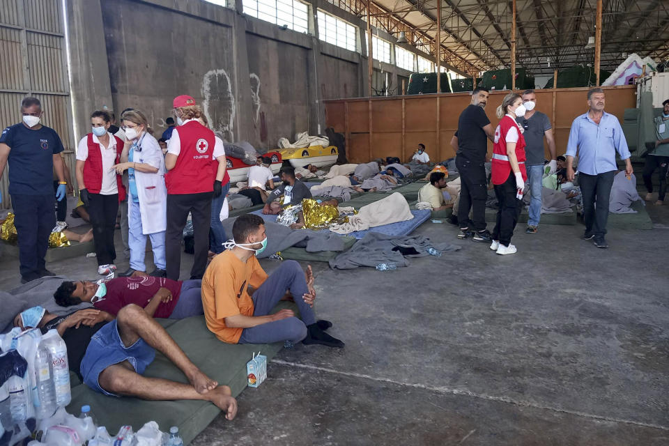 Survivors of a shipwreck rest at a warehouse at the port in Kalamata town, about 240 kilometers (150 miles) southwest of Athens, Wednesday, June 14, 2023. Authorities say at least 30 people have died after a fishing boat carrying dozens of migrants capsized and sank off the southern coast of Greece. A large search and rescue operation is underway. (www.argolikeseidhseis.gr via AP)
