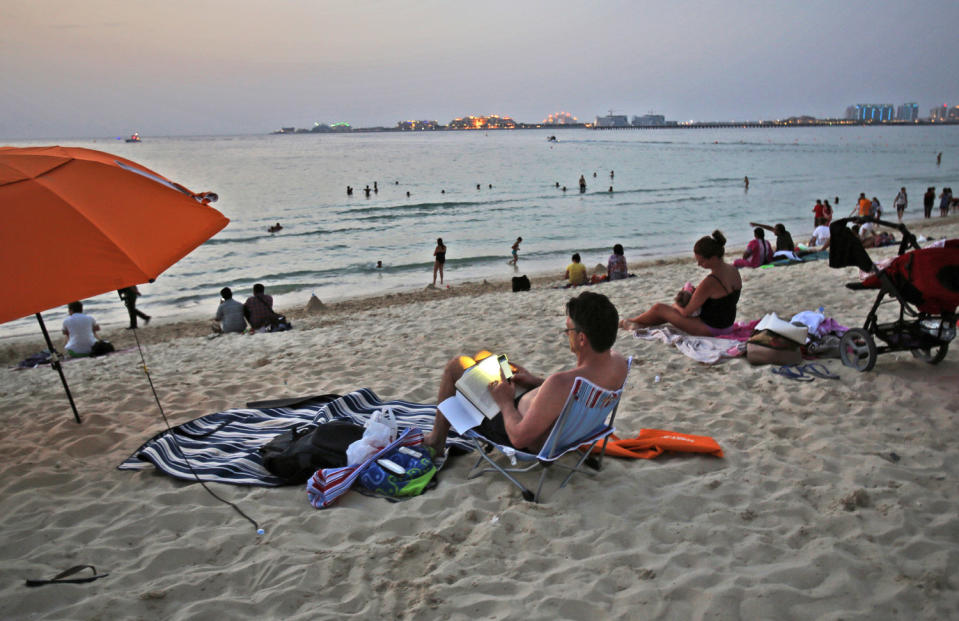 In this Saturday, April 19, 2014 photo, a man uses his mobile phone flashlight to read on the beach in Dubai, United Arab Emirates. The ribbon of beach nestled along the towering skyscrapers rising from Dubai’s man-made marina district is a rare spot in the Middle East, bringing together the conservatively dressed and the bikini-clad in a multiethnic mix of those with means and those still striving for a more comfortable life. (AP Photo/Kamran Jebreili)