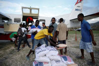 <p>Men carry sacks of rice out from an airplane loaded with food at the airport after Hurricane Matthew passes Jeremie, Haiti, October 7, 2016. (REUTERS/Carlos Garcia Rawlins)</p>