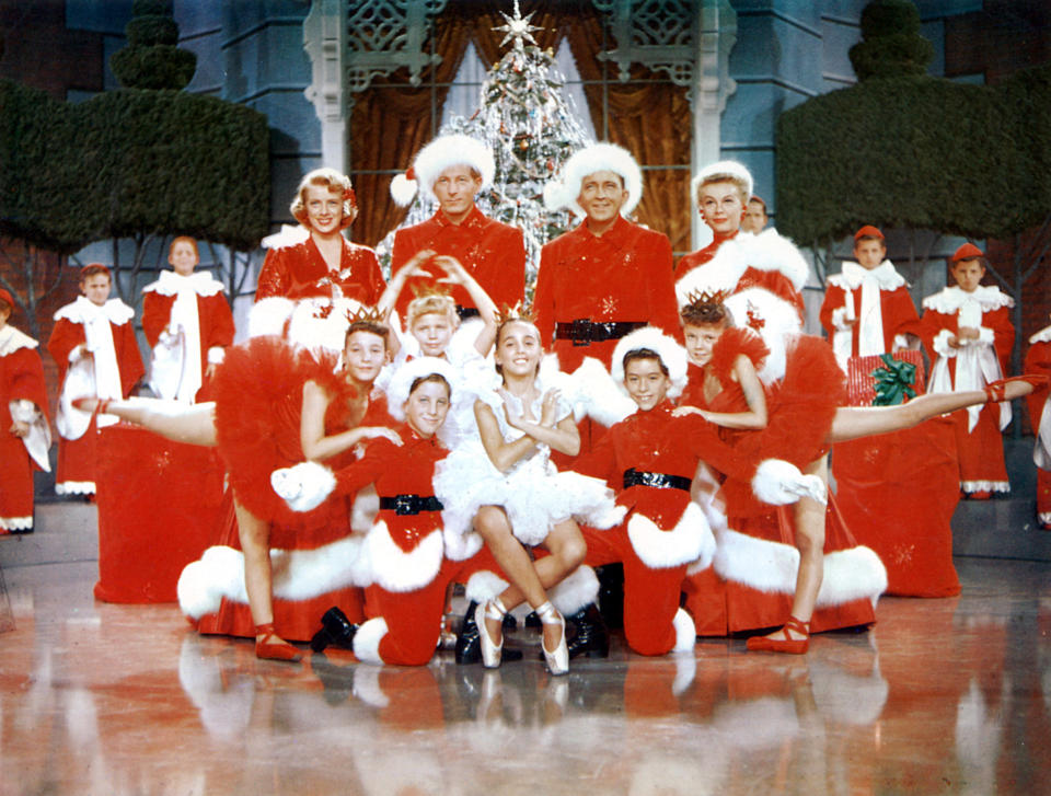 the company of white christmas posing in variously styled santa outfits