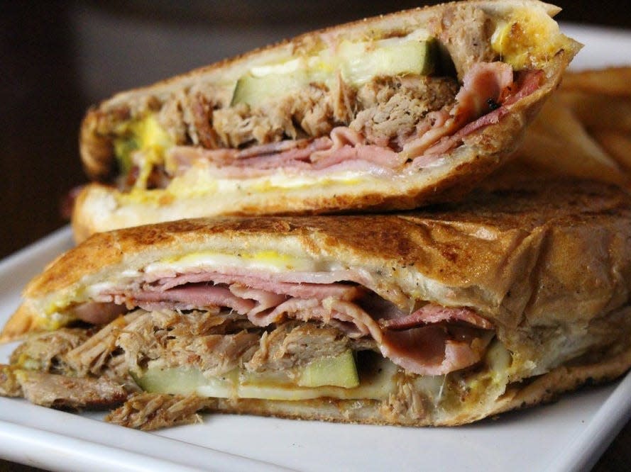 Cuban sandwich halves stacked on top of each other on a white plate