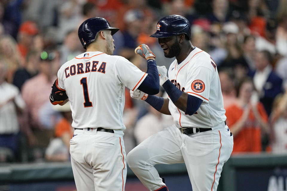 Houston Astros designated hitter Yordan Alvarez, right, is greeted by Carlos Correa near home plate after hitting a solo home run off Chicago White Sox starting pitcher Reynaldo Lopez during the fifth inning in Game 1 of a baseball American League Division Series Thursday, Oct. 7, 2021, in Houston. (AP Photo/David J. Phillip)