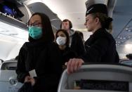 Passengers wear surgical masks as they board a British Airways flight from Terminal 5 at Heathrow Airport in London