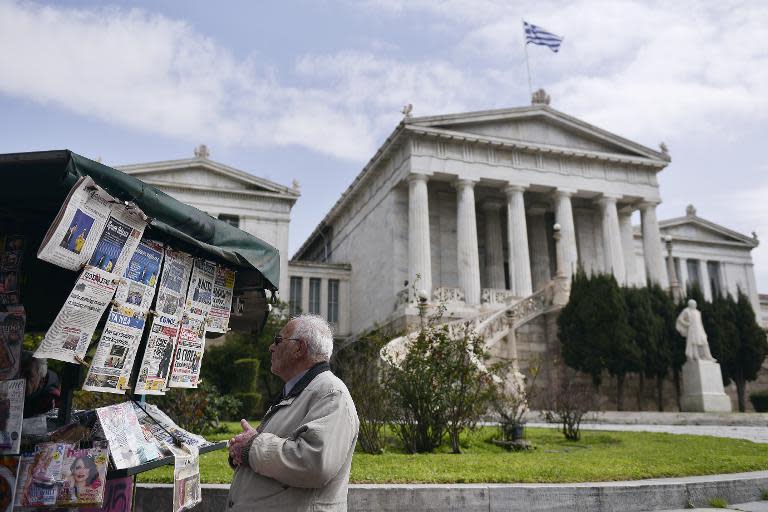 A man reads newspaper headlines in Athens on March 24, 2015