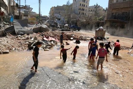 Children play with water from a burst water pipe at a site hit yesterday by an air strike in Aleppo's rebel-controlled al-Mashad neighbourhood. REUTERS/Abdalrhman Ismail