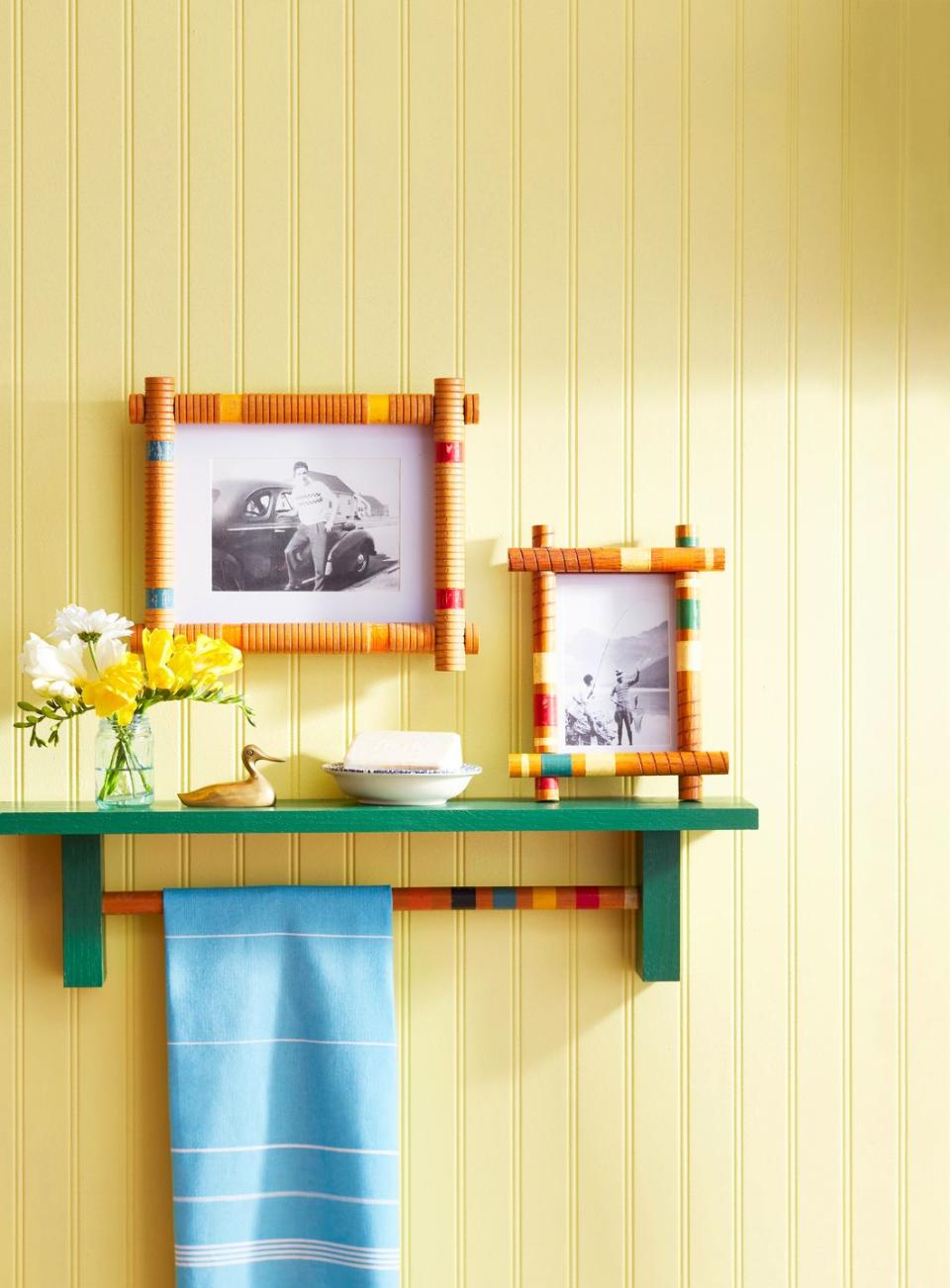 beadboard wall painted yellow and decorated with a green shelf and mounted picture frames