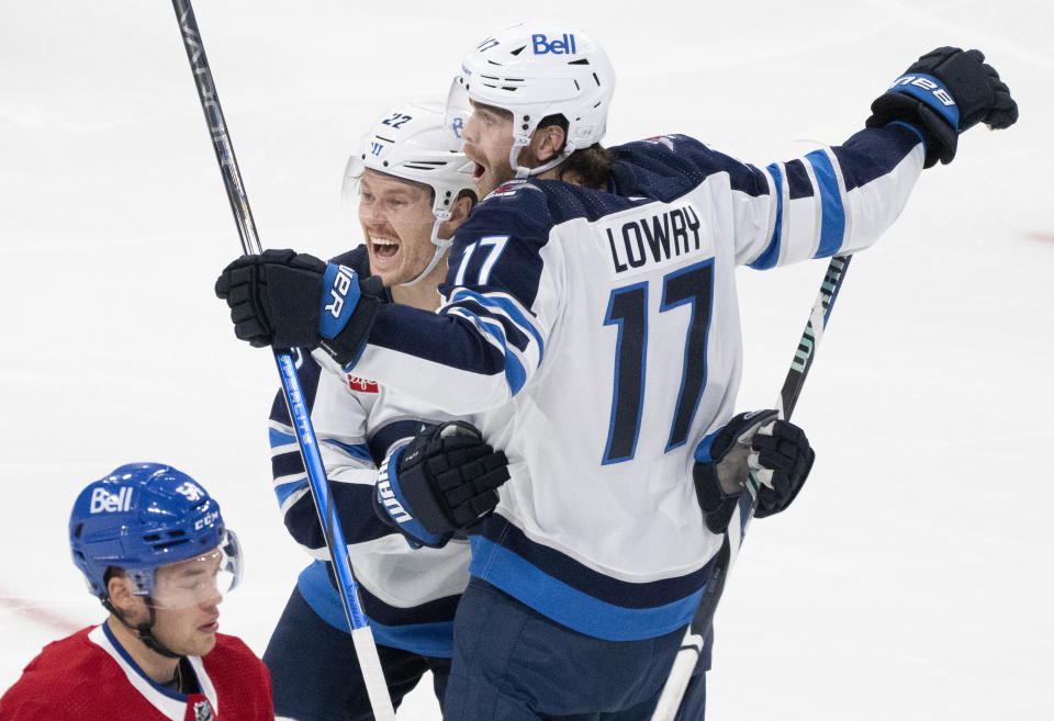 Winnipeg Jets' Adam Lowry (17) celebrates his goal with teammate Mason Appleton (22) as Montreal Canadiens' Jordan Harris (bottom) skates by during the second period of an NHL hockey game in Montreal on Saturday, Oct. 28, 2023. (Christinne Muschi/The Canadian Press via AP)