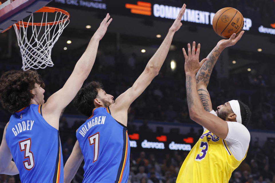 Los Angeles Lakers forward Anthony Davis (3) shoots as Oklahoma City Thunder guard Josh Giddey (3) and forward Chet Holmgren (7) defend during the first half of an NBA basketball game, Thursday, Nov. 30, 2023, in Oklahoma City. (AP Photo/Nate Billings)