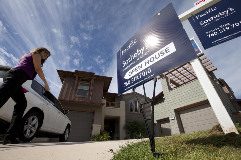 In this Wednesday, Nov. 14, 2012, photo, a woman walks towards a home for sale during a viewing for brokers in Leucadia, Calif. Average U.S. rates on fixed mortgages fell to fresh record lows this week, a trend that has helped the housing market start to recover this year. Mortgage buyer Freddie Mac says that the average rate on the 30-year loan dipped to 3.34 percent, the lowest on records dating back to 1971. That's down from 3.40 percent last week and the previous record low of 3.36 percent reached last month. (AP Photo/Gregory Bull)