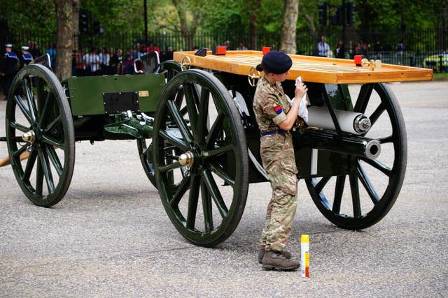Military personnel cleaning a gun carriage