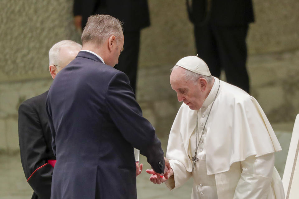 Pope Francis gets his hands sanitized at the start of his weekly general audience in the Pope Paul VI hall at the Vatican, Wednesday, Oct. 14, 2020. (AP Photo/Andrew Medichini)