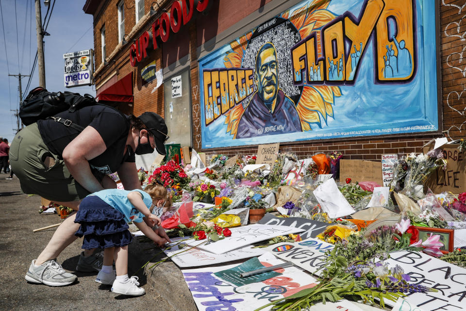 Jessica Knutson, and her daughter Abigail, 3, place flowers at a memorial to George Floyd, Sunday, May 31, 2020, in Minneapolis. Protests continued following the death of Floyd, who died after being restrained by Minneapolis police officers on May 25. (AP Photo/John Minchillo)