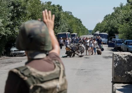 A member of the Ukrainian State Border Guard Service gives a sign to people to stop as they approach a checkpoint at the contact line between pro-Russian rebels and Ukrainian troops in Mayorsk
