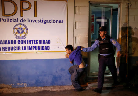 A policeman escorts a suspected gang member at a police station in San Pedro Sula, Honduras, September 20, 2018. REUTERS/Goran Tomasevic