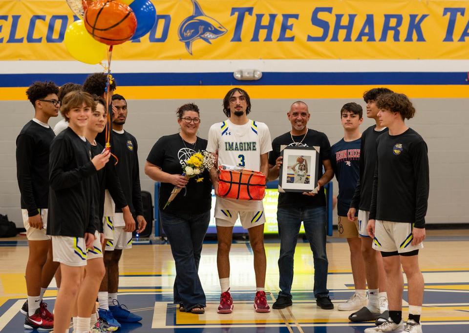 Imagine School at North Port basketball player Angelo Blas celebrates with his parents and Shark teammates scoring his 1,000th career point earlier this season.