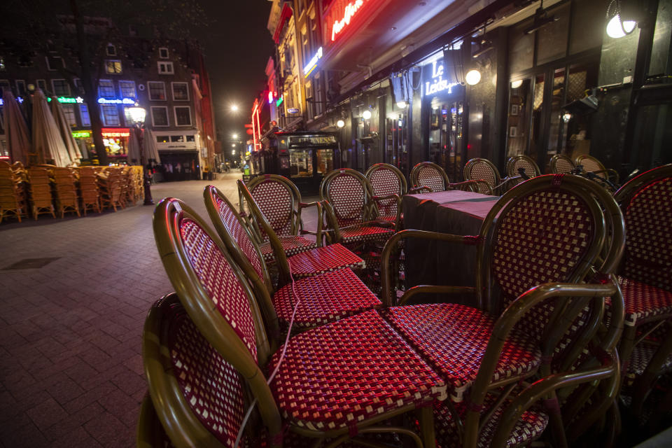 The bars are closed and terrace chairs are stacked on the popular Leidseplein in Amsterdam, Netherlands, Sunday, March 15, 2020, after a TV address of health minister Bruno Bruins who ordered all Dutch schools, cafes, restaurants, including coffeeshops, brothels, strip clubs and sport clubs to be closed from Sunday onwards as the government sought to prevent the further spread of coronavirus in the Netherlands. For most people, the new coronavirus causes only mild or moderate symptoms, such as fever and cough. For some, especially older adults and people with existing health problems, it can cause more severe illness, including pneumonia. (AP Photo/Peter Dejong)