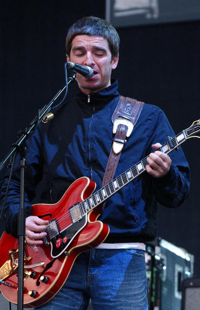 Noel Gallagher playing guitar on stage