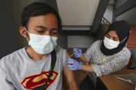 A man receives a shot of the Sinovac COVID-19 vaccine during a vaccination campaign at the Patriot Candrabhaga Stadium in Bekasi on the outskirts of Jakarta, Indonesia Friday, Nov. 26, 2021. Indonesia has significantly recovered from a mid-year spike in coronavirus cases and deaths that was one of the worst in the region, but with its vaccination drive stalling and holidays approaching, experts and officials warn the island nation could be set soon for another surge. (AP Photo/Achmad Ibrahim)