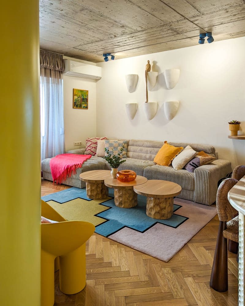 white living room with large sofa, circles coffee table, pops of color,