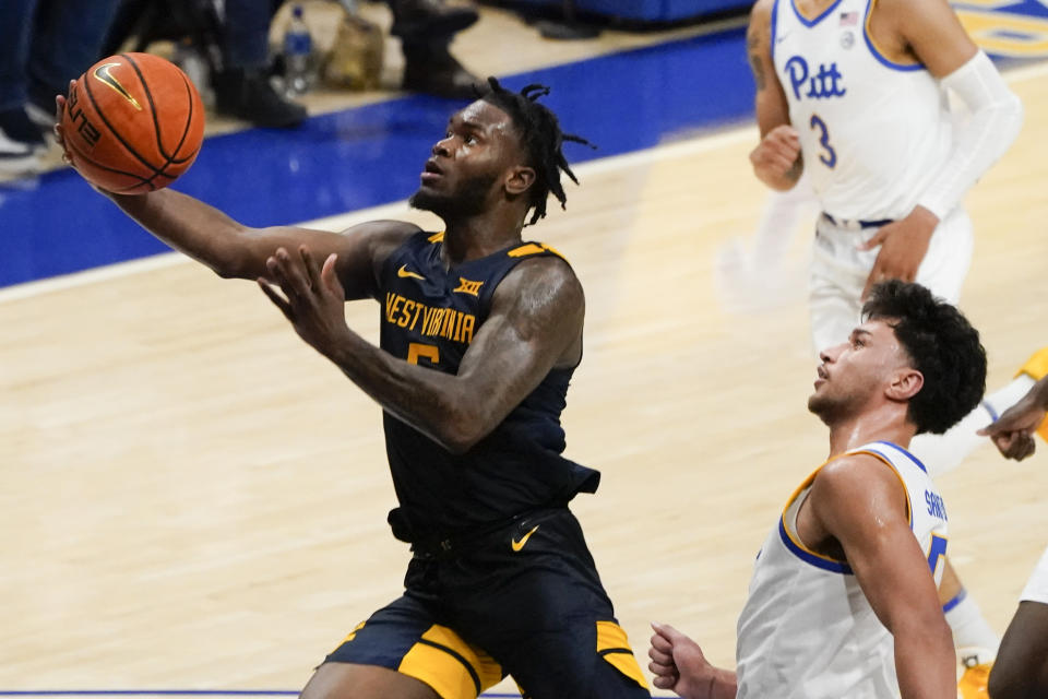 West Virginia's Joe Toussaint, left, scores past Pittsburgh's Nate Santos during the second half of an NCAA college basketball game, Friday, Nov. 11, 2022, in Pittsburgh. (AP Photo/Keith Srakocic)
