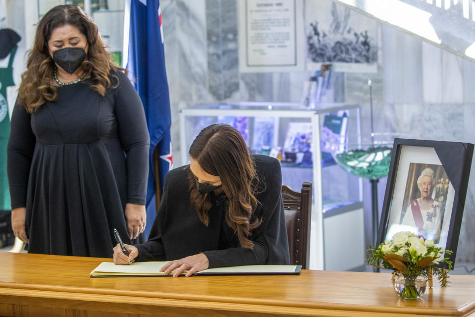 New Zealand Prime Minister Jacinda Ardern, right, signs the book of condolences as Governor-General Dame Cindy Kiro watches at Parliament, Wellington at the Beehive in Wellington, New Zealand, Friday, Sept. 9, 2022. Queen Elizabeth II, Britain's longest-reigning monarch and a symbol of stability in a turbulent era for her country and the world, died Thursday, Sept. 8 after 70 years on the throne. She was 96. (Mark Mitchell/New Zealand Herald via AP)