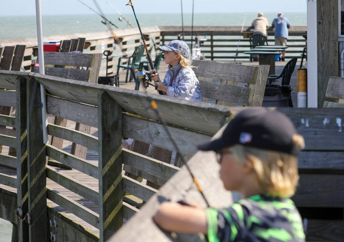 Miles and Lucy Rail, ages 8 and 6, of Utah fish from the Garden City Pier while visiting the area with their family. October 10, 2022.