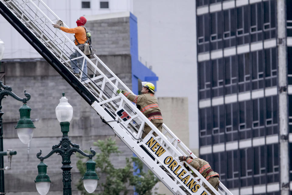 A rescued worker, left, and a firefighter look back at the damaged building after a large portion of a hotel under construction suddenly collapsed in New Orleans on Saturday, Oct. 12, 2019. Several construction workers had to run to safety as the Hard Rock Hotel, which has been under construction for the last several months, came crashing down. It was not immediately clear what caused the collapse or if anyone was injured. (Scott Threlkeld/The Advocate via AP)