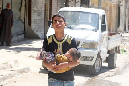 A civilian evacuates a baby from a site hit by airstrikes in the rebel held area of Aleppo's al-Fardous district, Syria, April 29, 2016. REUTERS/Abdalrhman Ismail