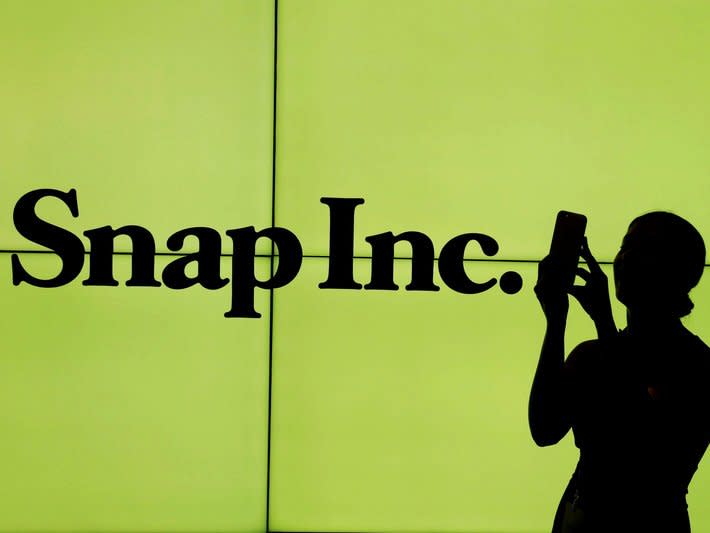 FILE PHOTO - A woman stands in front of the logo of Snap Inc. on the floor of the New York Stock Exchange (NYSE) while waiting for Snap Inc. to post their IPO, in New York City, New York, U.S. on March 2, 2017. REUTERS/Lucas Jackson/File Photo