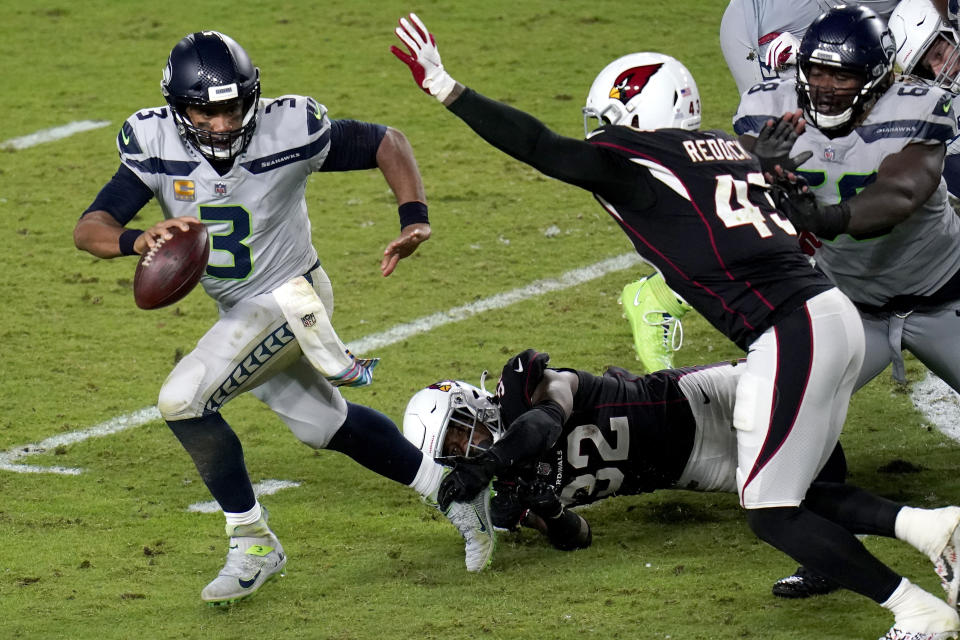 Seattle Seahawks quarterback Russell Wilson (3) escapes the reach of Arizona Cardinals strong safety Budda Baker (32) as outside linebacker Haason Reddick (43) pursues during the second half of an NFL football game, Sunday, Oct. 25, 2020, in Glendale, Ariz. (AP Photo/Ross D. Franklin)