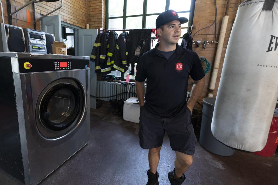 Firefighter Kevin Ceurvels stands beside an industrial washing machine used to clean turnout gear at the Engine 21 fire station, Thursday, Aug. 24, 2023, in the Dorchester neighborhood of Boston. (AP Photo/Michael Dwyer)