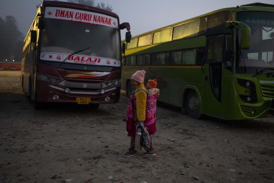 A tea vendor carrying her young daughter looks for customers at a bus parking of pilgrims arriving at the Pashupatinath Temple in Kathmandu, Nepal, Jan. 12, 2024. The centuries-old temple is one of the most important pilgrimage sites in Asia for Hindus. Nepal and India are the world’s two Hindu-majority nations and share a strong religious affinity. Every year, millions of Nepalese and Indians visit Hindu shrines in both countries to pray for success and the well-being of their loved ones. (AP Photo/Niranjan Shrestha)