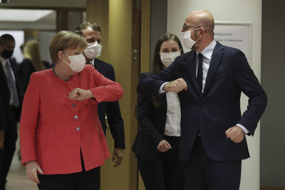 European Council President Charles Michel, right, greets German Chancellor Angela Merkel, left, with an elbow bump during a round table meeting at an EU summit in Brussels, Friday, July 17, 2020. Leaders from 27 European Union nations meet face-to-face on Friday for the first time since February, despite the dangers of the coronavirus pandemic, to assess an overall budget and recovery package spread over seven years estimated at some 1.75 trillion to 1.85 trillion euros. (Stephanie Lecocq, Pool Photo via AP)