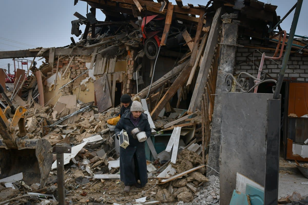 Residents carry their belongings as they leave their home ruined in Saturday’s Russian rocket attack in Zaporizhzhya, Ukraine, on January 1  (AP)