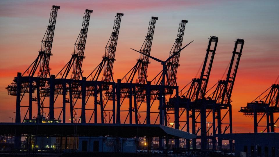 Hinter hochgeklappten Containerbrückenkränen im Hamburger Hafen geht die Sonne unter. Die Corona-Krise bremst den weltweiten Handel aus.