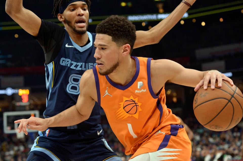 Phoenix Suns guard Devin Booker (1) handles the ball against Memphis Grizzlies guard Ziaire Williams (8) in the first half of an NBA basketball game Friday, April 1, 2022, in Memphis, Tenn. (AP Photo/Brandon Dill)