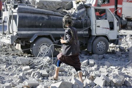 A man walks past a damaged water tanker truck at the site of a Saudi-led air strike in Yemen's capital Sanaa January 4, 2016. REUTERS/Khaled Abdullah