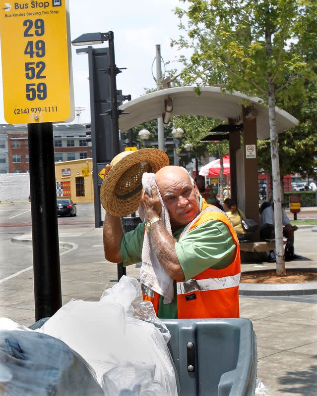 FILE PHOTO: A sanitation worker wipes sweat from his head as he works during a prolonged heat wave in Dallas, Texas
