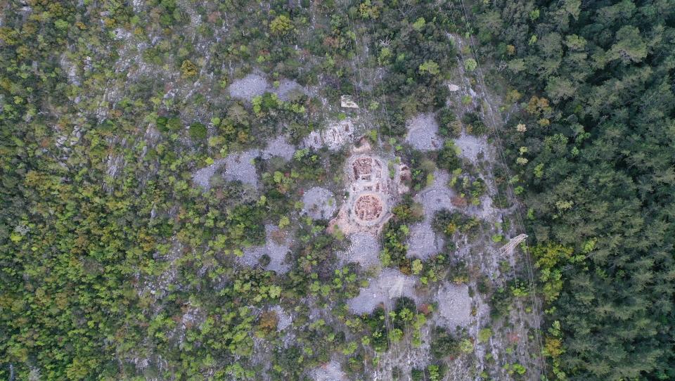 Aerial view of a mound necropolis in Croatia. We see a lot of trees and some bare stone patches.