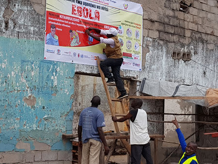 Workers fix an Ebola awareness poster in Tchomia, Democratic Republic of Congo, to raise awareness about Ebola in the local community, on October 9, 2018. WHO/Aboulaye Cisse/Handout via REUTERS