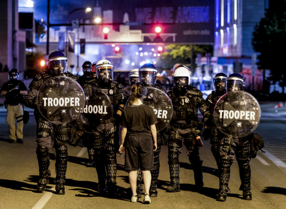 A woman stands in front of troopers in riot gear as police deployed tear gas and stun grenades to clear the area around Akron City Hall and Akron Police Station during a protest over the killing of Jayland Walker, in Akron, Ohio, July 3, 2022. (Matthew Hatcher / AFP via Getty Images file)
