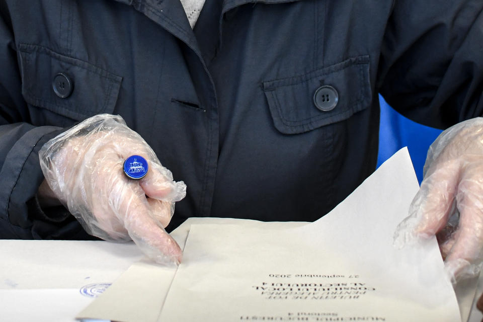 A woman wearing gloves to protect against COVID-19 infection prepares to cast her vote in Bucharest, Romania, Sunday, Sept. 27, 2020. Polls have opened in Romania’s municipal election, which is being seen as a test of how the next general election on Dec. 6 will unfold for the country’s minority-led government. (AP Photo/Andreea Alexandru)