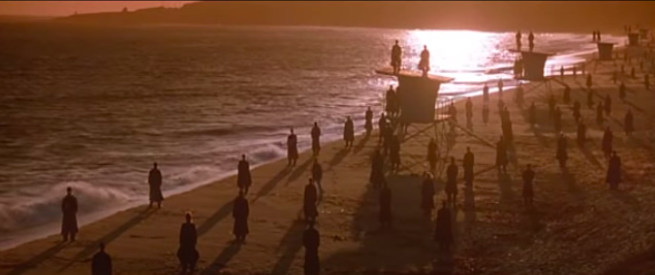 A large group of people stand on the beach