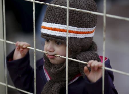 A Syrian boy looks through a gate as others wait to cross into Syria at Oncupinar border crossing in the southeastern city of Kilis, Turkey February 11, 2016. REUTERS/Osman Orsal