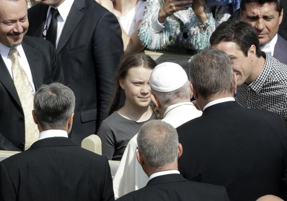 Pope Francis, back to camera, greets Swedish teenage environmental activist Greta Thunberg, center, during his weekly general audience in St. Peter's Square, at the Vatican, Wednesday, April 17, 2019. (AP Photo/Gregorio Borgia)
